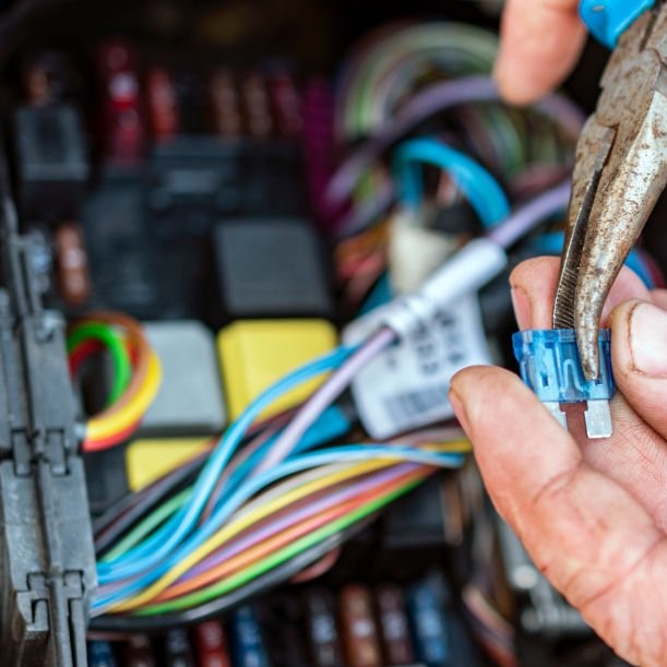 Mechanic with pliers checking the car fuse box of electric car